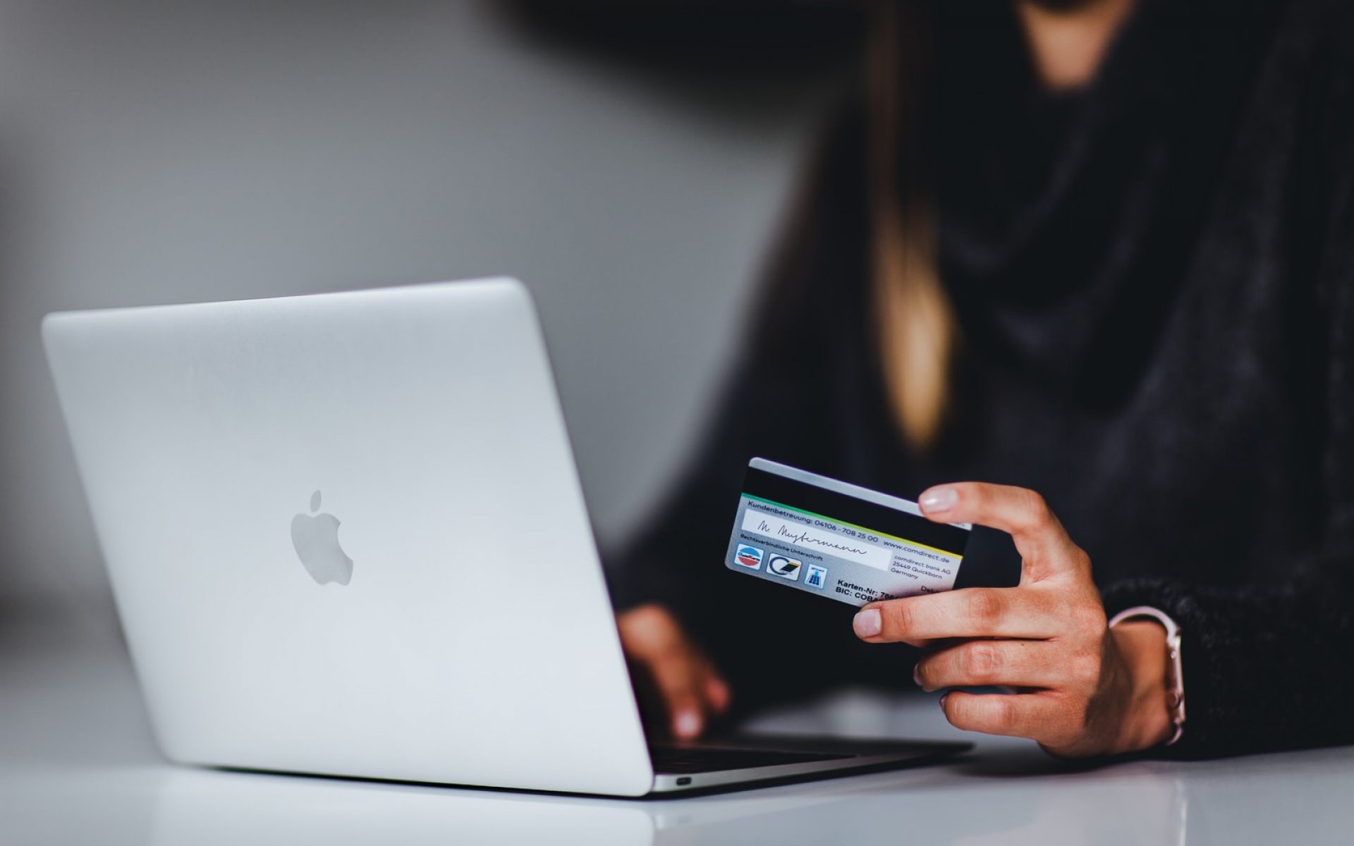 woman holding black smartphone near silver macbook