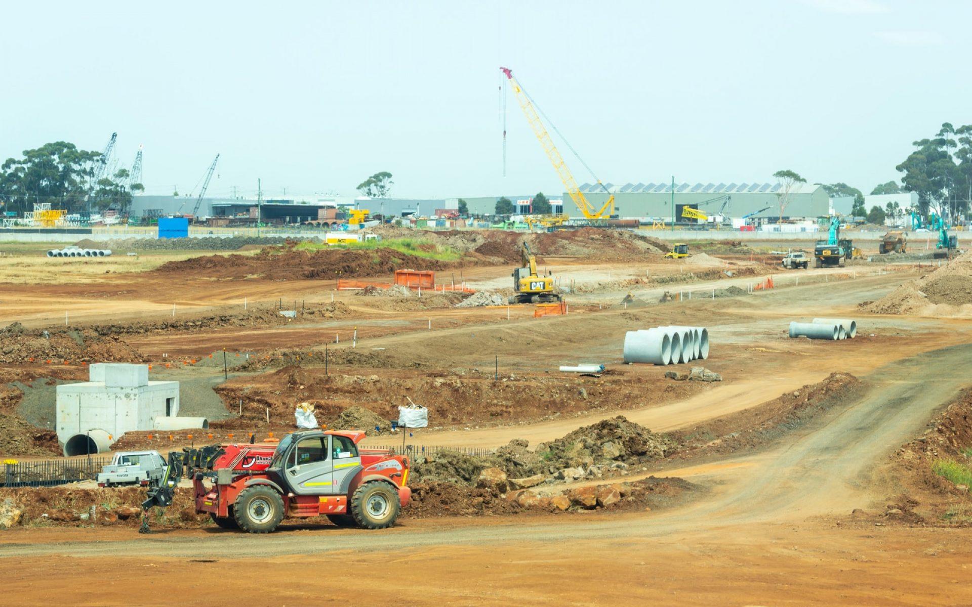 orange and white heavy equipment on muddy road during daytime